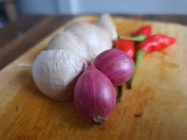 Mutfak tarifleri için baharat ya da aroma malzemeleri. Beyaz sarımsak, acı biber ve ahşap kesme tahtasındaki kırmızı soğan.