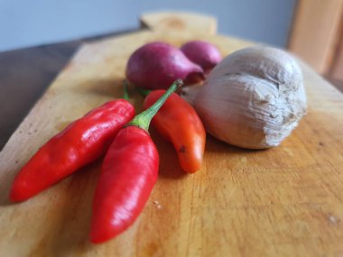 Mutfak tarifleri için baharat ya da aroma malzemeleri. Beyaz sarımsak, acı biber ve ahşap kesme tahtasındaki kırmızı soğan.