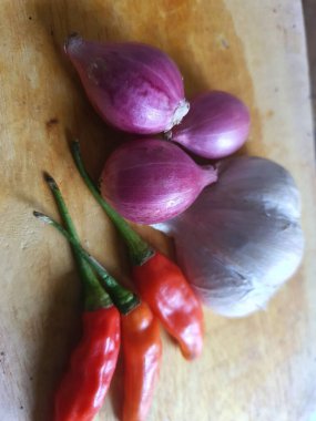 Mutfak tarifleri için baharat ya da aroma malzemeleri. Beyaz sarımsak, acı biber ve ahşap kesme tahtasındaki kırmızı soğan.