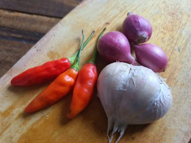 Mutfak tarifleri için baharat ya da aroma malzemeleri. Beyaz sarımsak, acı biber ve ahşap kesme tahtasındaki kırmızı soğan.
