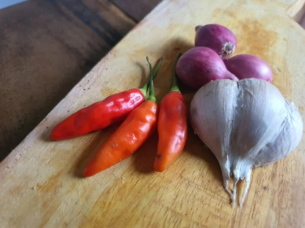 Mutfak tarifleri için baharat ya da aroma malzemeleri. Beyaz sarımsak, acı biber ve ahşap kesme tahtasındaki kırmızı soğan.