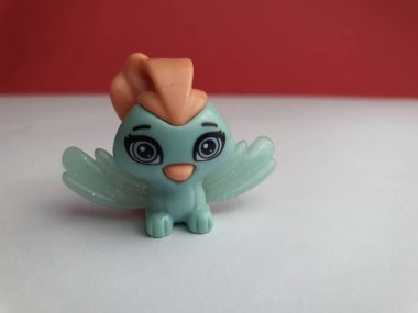 Beyaz zemin üzerinde duran sevimli bir kuşun küçük plastik oyuncağı..