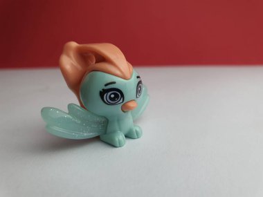 Beyaz zemin üzerinde duran sevimli bir kuşun küçük plastik oyuncağı..