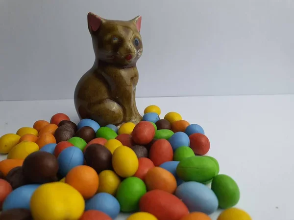 Vinyl figurine of a cat character portrayed with candy balls spread.