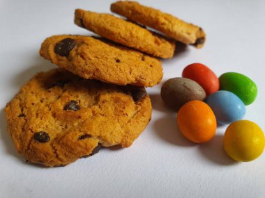 Beyaz arkaplanda renkli şeker topları ve kurabiye süsü.