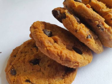 Beyaz arka planda çikolata parçalı çıtır kurabiyeler.