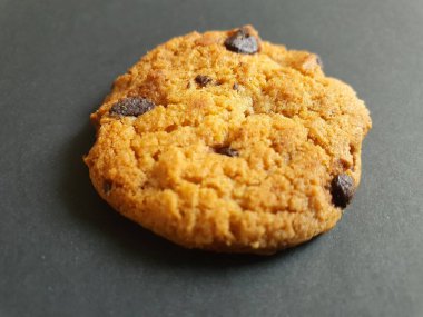 Siyah arka planda çikolata parçalı çıtır kurabiyeler.