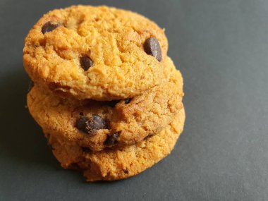 Siyah arka planda çikolata parçalı çıtır kurabiyeler.