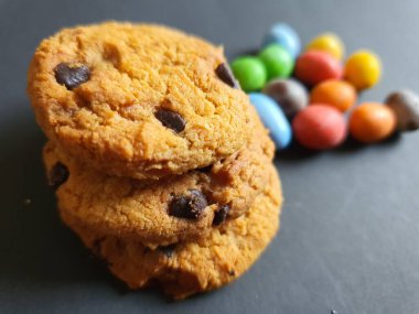 Siyah arkaplanda renkli şeker topları ve kurabiye süsü.