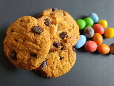 Siyah arkaplanda renkli şeker topları ve kurabiye süsü.