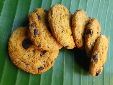 Yeşil muz yaprağı arka planında ev yapımı çikolatalı kurabiyeler. İlgili herhangi bir tasarım amacı için gıda temalı arkaplan.