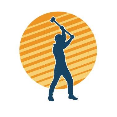 Çalışan bir işçinin silueti balyoz aletini kullanarak hareket halinde poz verir.