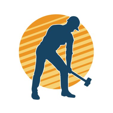 Çalışan bir işçinin silueti balyoz aletini kullanarak hareket halinde poz verir.