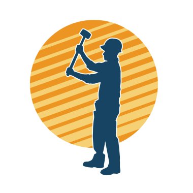 Çalışan bir işçinin silueti balyoz aletini kullanarak hareket halinde poz verir.