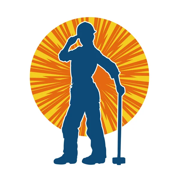 Çalışan bir işçinin silueti balyoz aletini kullanarak hareket halinde poz verir.