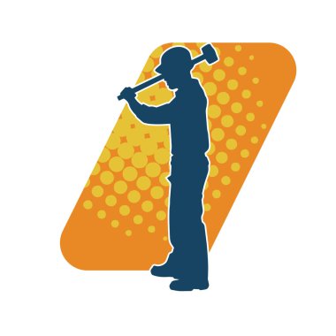 Çalışan bir işçinin silueti balyoz aletini kullanarak hareket halinde poz verir.