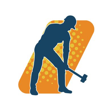 Çalışan bir işçinin silueti balyoz aletini kullanarak hareket halinde poz verir.