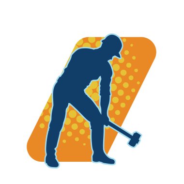 Çalışan bir işçinin silueti balyoz aletini kullanarak hareket halinde poz verir.