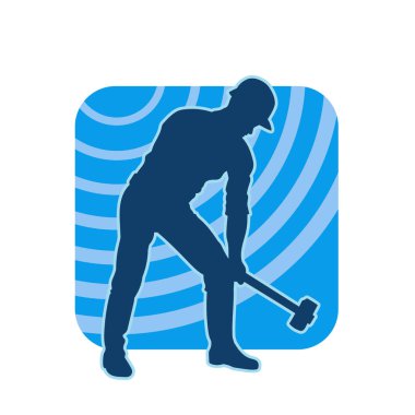 Çalışan bir işçinin silueti balyoz aletini kullanarak hareket halinde poz verir.