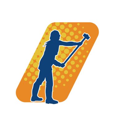 Çalışan bir işçinin silueti balyoz aletini kullanarak hareket halinde poz verir.