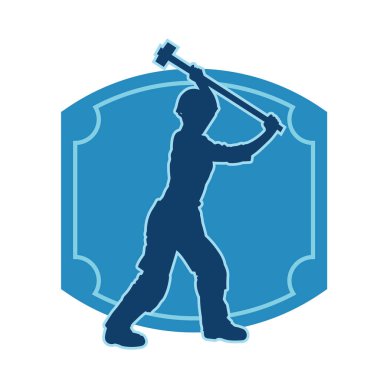 Çalışan bir işçinin silueti balyoz aletini kullanarak hareket halinde poz verir.