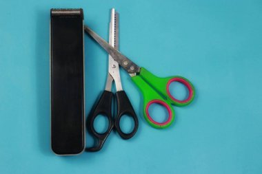 Mavi arka planda iki makas ve bir saç makası.