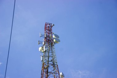 Cep telefonu anteninin altından bir fotoğraf ve mavi gökyüzü arkaplanı. Yüksek hızlı 2g, 3g, 4g, 5g veri kullanımı kablosuz ağ teknolojisi.