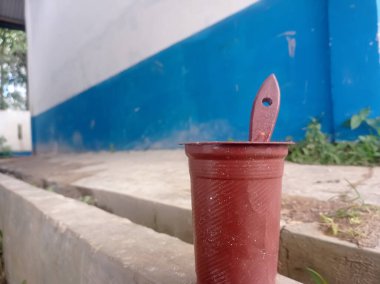 Plastik bardak ve kahverengi boya kabı olarak kullanılan bir fırça, plastik atık kullanımı.