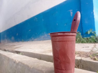 Plastik bardak ve kahverengi boya kabı olarak kullanılan bir fırça, plastik atık kullanımı.