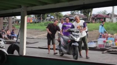 Batı Kutai, Doğu Kalimantan, Endonezya - 21 Ekim 2022 - Bazı adamlar tekneye iki tekerlekli araçlar, deniz ulaşımı, su taşımacılığı.