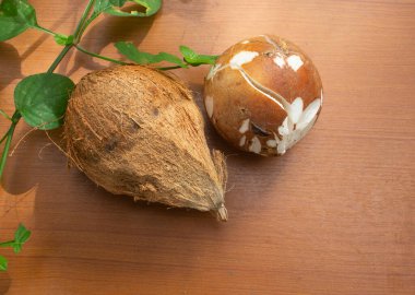 Soyulmuş hindistan cevizi ve kahverengi arka planda yapraklar