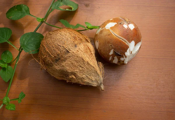 皮をむいたココナッツと茶色の背景に葉 — ストック写真