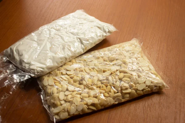 Çiğ tempeh ya da tempeh ve kahverengi masadaki plastik içinde çiğ soya çekirdeği. Tempe mayalanmış soya fasulyesinden yapılan geleneksel bir Endonezya yemeğidir..