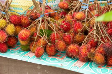 Masanın üzerine konulan çimenler, sokak yiyecekleri satıcıları tarafından satılan Rambutan.