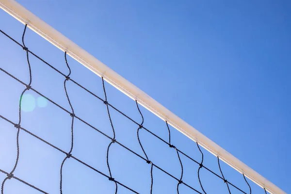 Plaj voleybolunun çapraz yakın çekim parçası. Arka planda açık mavi gökyüzü var.