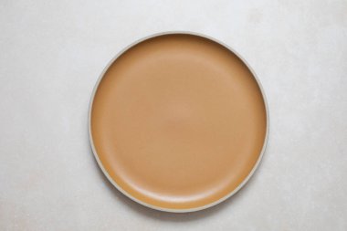 Closeup top view on empty ceramic yellow plate on light pink travertine stone textured background