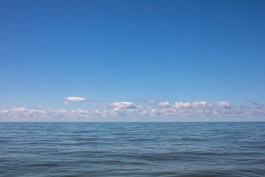 Pacific ocean view with the horizon line and blue sky with remote clouds