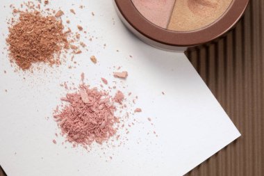 Üzerinde göz gölgesi olan beyaz kağıt üzerinde pembe ve bej renkli göz gölgeleri olan bir numunenin yakın görüntüsü.