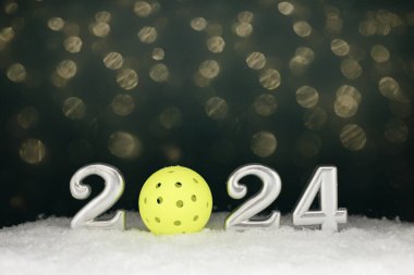 Yeni yıl gümüşü 2024 tabelası üzerinde sarı bir yankesicilik, koyu yeşil bir zemin ve bulanık ışıklar var.