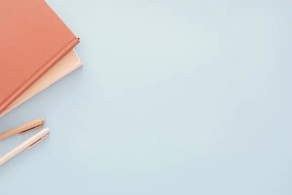 stock image Flat lay of two planners books in light pink and terracotta colors and two beige pens on blue background with copyspace