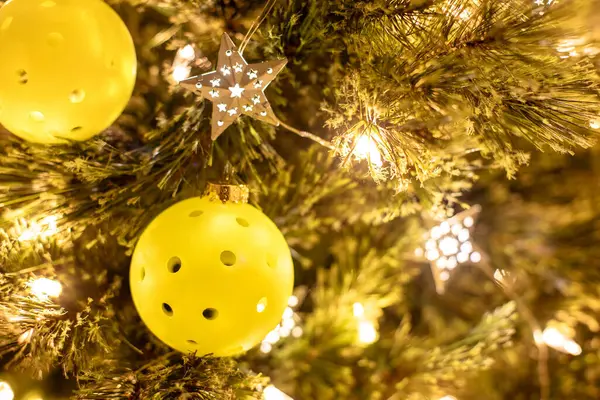 Noel ağacını süsleri, parlak ışıkları ve yıldızları olan bir noel ağacının yakın görüntüsü. Seçici odaklanma. Noel arkaplanı Pickleball.