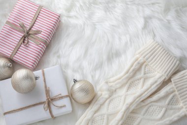 İki paketlenmiş Noel hediyesinin, çorapların ve sahte kürklü altın süslemelerin yakın görüntüsü.