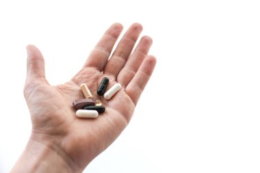 Beyaz arka planı ve metin alanı olan günlük takviye haplarını tutan beyaz bir adamın yakın çekimi.