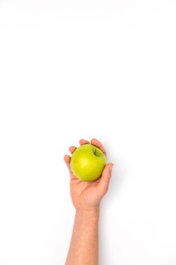 Beyaz arka planda yeşil bir Granny Smith elması tutan beyaz bir kadın eli.