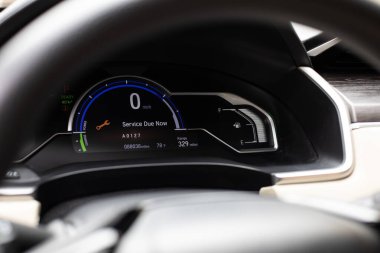 Hız göstergesi, yakıt göstergesi ve gerekli hizmet alarmını gösteren modern bir gösterge panelinin yakın çekimi. Direksiyon simidi aracılığıyla iç görünüm.