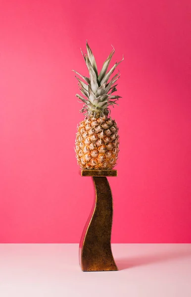 成熟的菠萝站在一个金黄色的高立场与一个充满活力的粉红色背景 最低限度创意水果的概念 垂直框架 — 图库照片