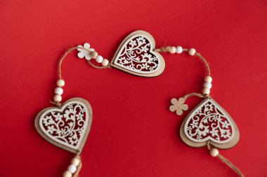 Wooden hearts with bio ornament on a red background.