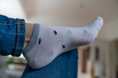 Legs in socks with hearts, jeans, grey.