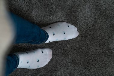 Legs in socks with hearts, jeans, grey.