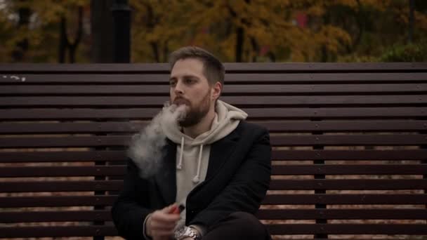 Hombre Fuma Cigarrillo Electrónico Parque Sentado Banco Primavera — Vídeo de stock